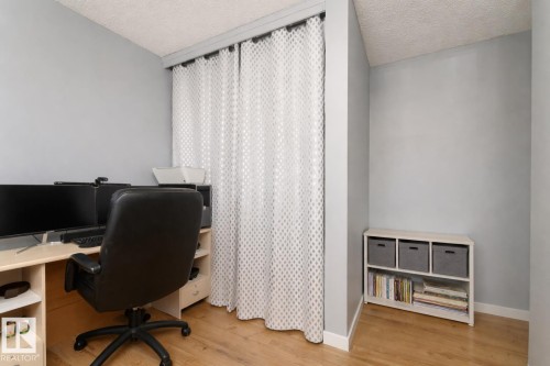 This versatile room features light hardwood flooring, a neutral grey wall color, and a textured ceiling - 16131 109 Avenue, Edmonton, AB - Indoor Photo Showing Office