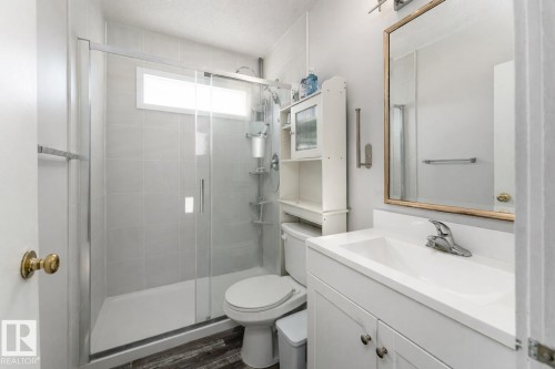 The bathroom features a glass-enclosed shower with light-colored tile walls and a window - 16131 109 Avenue, Edmonton, AB - Indoor Photo Showing Bathroom