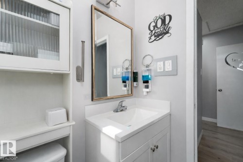 This bathroom features a white vanity with a white countertop and a mirror with a gold frame - 16131 109 Avenue, Edmonton, AB - Indoor Photo Showing Bathroom