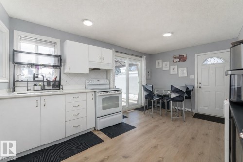 The kitchen features white cabinetry, a white electric range, and light-colored countertops - 16131 109 Avenue, Edmonton, AB - Indoor Photo Showing Other Room