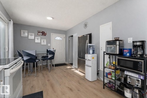 This open concept space features light-colored flooring, a white range, and a full-size stainless steel refrigerator - 16131 109 Avenue, Edmonton, AB - Indoor