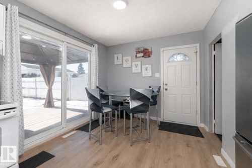 This living space features light wood-style flooring and a sliding glass door that opens to an outdoor deck area - 16131 109 Avenue, Edmonton, AB - Indoor Photo Showing Dining Room