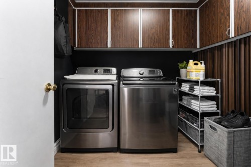Dedicated laundry area featuring a washer and dryer, wood-look flooring, and dark wood cabinetry - 16131 109 Avenue, Edmonton, AB - Indoor Photo Showing Laundry Room