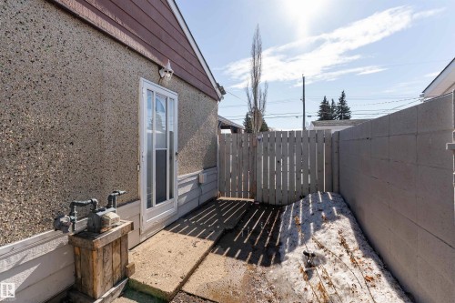 The property features a concrete patio area, bordered by a wooden fence and a concrete block wall - 16131 109 Avenue, Edmonton, AB - Outdoor With Exterior