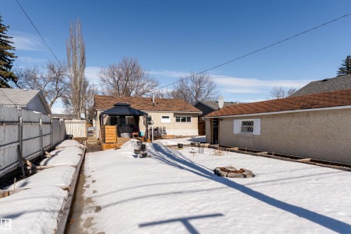 The property features a spacious yard with a fire pit, a wooden deck with a gazebo, and a detached garage with a brown shingle roof - 16131 109 Avenue, Edmonton, AB - Outdoor
