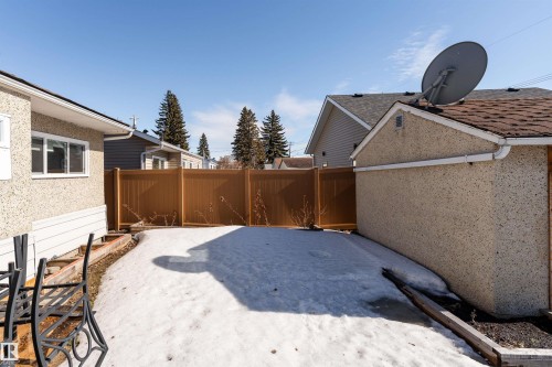 The property features a private yard with a brown fence and a separate building with a shingled roof - 16131 109 Avenue, Edmonton, AB - Outdoor