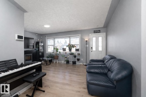 Living room featuring light-colored flooring, a large window, and a white front door with glass inserts - 16131 109 Avenue, Edmonton, AB - Indoor Photo Showing Living Room