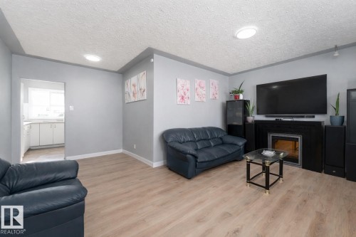 Living area featuring light wood-style flooring, a fireplace with a black surround, and light grey walls - 16131 109 Avenue, Edmonton, AB - Indoor Photo Showing Living Room