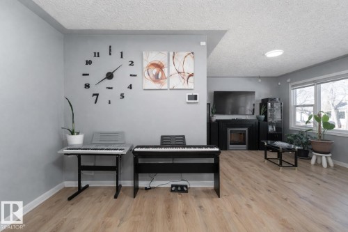 This inviting living space features light-colored flooring, light grey walls, and a fireplace with a dark mantel - 16131 109 Avenue, Edmonton, AB - Indoor With Fireplace