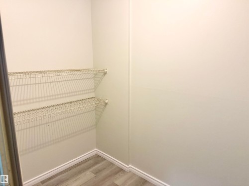 This closet provides convenient storage with two tiers of wire shelving and a light-toned wood-style floor - 307 1620 48 Street, Edmonton, AB - Indoor With Storage