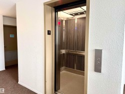 The property provides elevator access, featuring a modern elevator car with wood-paneled walls and a mirrored ceiling - 