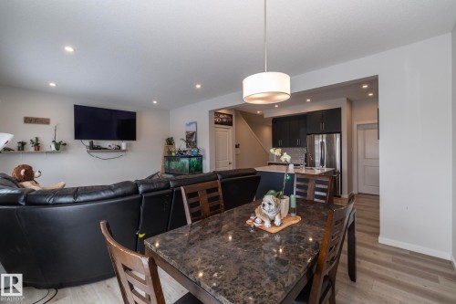 Open concept living area with recessed lighting, light-toned flooring, and a modern kitchen featuring dark cabinetry and stainless steel appliances - 159 Larch Crescent, Leduc, AB - Indoor Photo Showing Dining Room