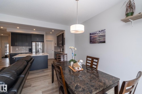 This open-concept living area features a kitchen with dark cabinetry, stainless steel appliances, and an island with a sink - 159 Larch Crescent, Leduc, AB - Indoor Photo Showing Dining Room