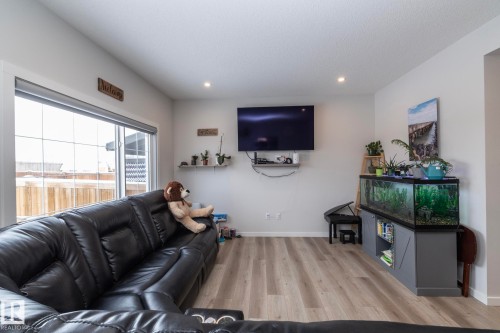 The living area features light-toned flooring, recessed lighting, and a large window providing views of the outdoor fence - 159 Larch Crescent, Leduc, AB - Indoor