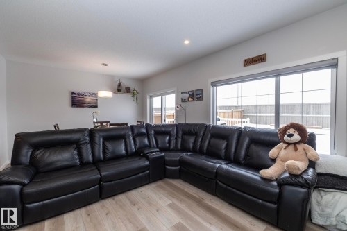 The living area features light-toned flooring, recessed lighting, and a window with a glass sliding door - 159 Larch Crescent, Leduc, AB - Indoor Photo Showing Living Room