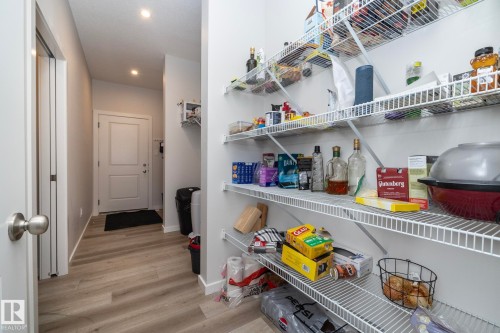 This property features a pantry with white wire shelving, a light-colored wood floor, and a white interior door - 159 Larch Crescent, Leduc, AB - Indoor