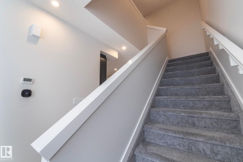 The staircase features carpeted steps and white railings - 159 Larch Crescent, Leduc, AB - Indoor Photo Showing Other Room