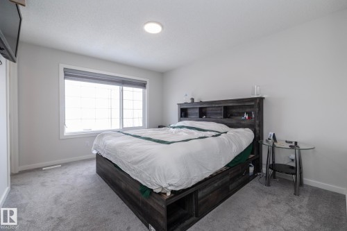The bedroom features light grey carpeting, a window with a blind, and a ceiling light fixture - 159 Larch Crescent, Leduc, AB - Indoor Photo Showing Bedroom