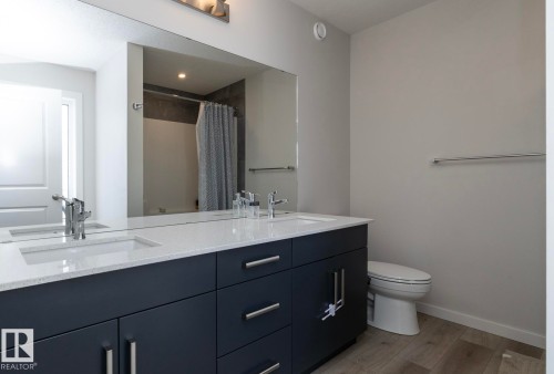 Bathroom featuring a double vanity with dark cabinetry, integrated sinks, and polished chrome faucets - 159 Larch Crescent, Leduc, AB - Indoor Photo Showing Bathroom