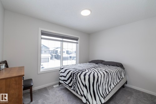 This room features a large window with blinds, light gray walls, and carpeting - 159 Larch Crescent, Leduc, AB - Indoor Photo Showing Bedroom