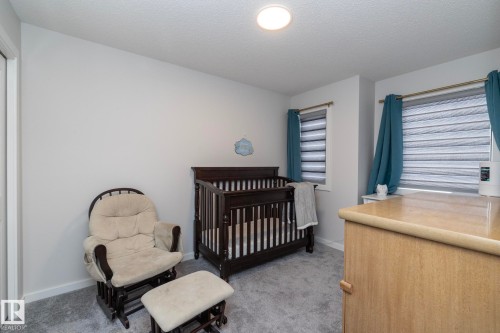 This room features light gray walls, plush gray carpeting, and two windows with blinds and teal curtains - 159 Larch Crescent, Leduc, AB - Indoor Photo Showing Bedroom