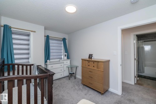 This room features light grey carpeting, two windows with blinds and teal curtains, and a ceiling light fixture - 159 Larch Crescent, Leduc, AB - Indoor Photo Showing Bedroom