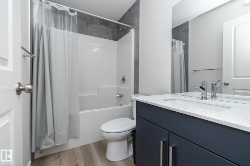 Contemporary bathroom featuring a vanity with a white countertop, chrome faucet, and dark cabinetry - 159 Larch Crescent, Leduc, AB - Indoor Photo Showing Bathroom