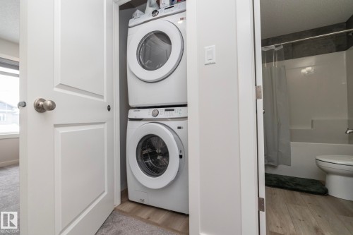 Compact laundry area featuring a stacked washer and dryer unit, conveniently located within a white bi-fold closet - 159 Larch Crescent, Leduc, AB - Indoor Photo Showing Laundry Room