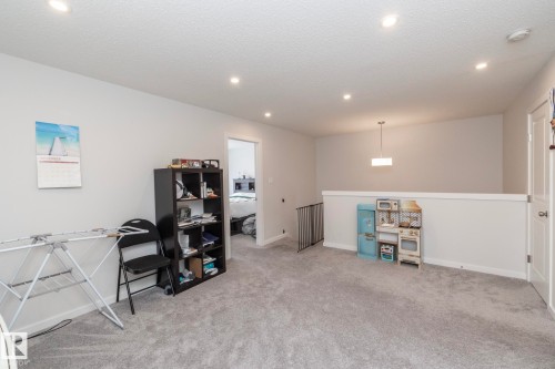 The property features an open area with light grey carpeting and light-colored walls - 159 Larch Crescent, Leduc, AB - Indoor