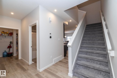 The entryway features light wood-style flooring, a staircase with gray carpeting and white railings, and recessed lighting - 159 Larch Crescent, Leduc, AB - Indoor Photo Showing Other Room