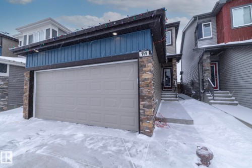 The property features an attached garage with a light-colored door, complemented by stone facade accents - 159 Larch Crescent, Leduc, AB - Outdoor