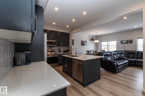 The property features an open-concept layout with a kitchen island and stainless steel appliances - 159 Larch Crescent, Leduc, AB - Indoor Photo Showing Kitchen
