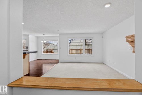 Bright and open living space featuring large windows, a wooden mantelpiece, and a combination of carpet and hardwood flooring - 978 Rutherford Road Sw, Edmonton, AB - Indoor Photo Showing Living Room