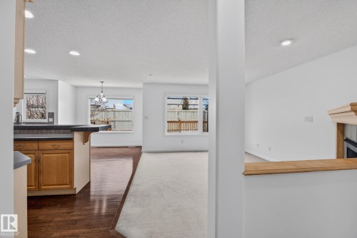 Open concept living space featuring a kitchen with wood cabinetry and a breakfast bar, hardwood flooring, and large windows providing natural light - 978 Rutherford Road Sw, Edmonton, AB - Indoor Photo Showing Other Room