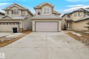 The property features a two-story exterior with light-colored siding, a two-car garage with a light-colored door, and a concrete driveway - 978 Rutherford Road Sw, Edmonton, AB  - Outdoor With Facade 
