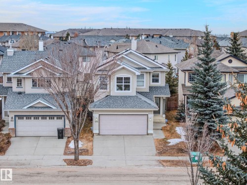 The property features a two-story design with light-colored siding and a grey shingled roof - 978 Rutherford Road Sw, Edmonton, AB - Outdoor With Facade