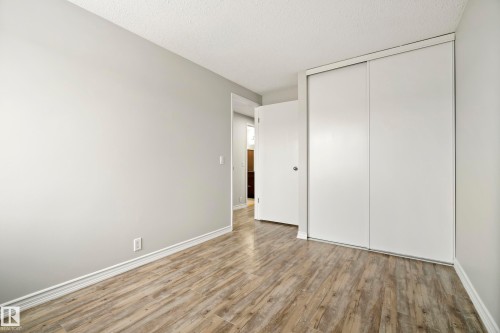 This room features light-toned walls, wood-style flooring, and a closet with sliding doors - 3311 139 Avenue, Edmonton, AB - Indoor Photo Showing Other Room