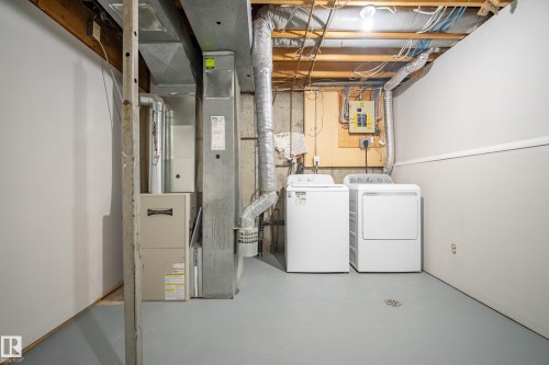 The utility area features a washer and dryer, with exposed ceiling beams, and a floor drain - 3311 139 Avenue, Edmonton, AB - Indoor Photo Showing Laundry Room