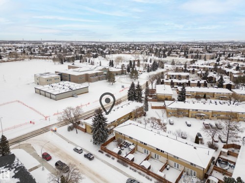 Aerial view of the property and its surrounding area, featuring several residential buildings with snow-covered roofs, and a large open field in the background - 3311 139 Avenue, Edmonton, AB - Outdoor With View