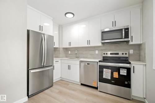 The kitchen features white cabinetry, stainless steel appliances, light countertops, and a light-colored backsplash - 3311 139 Avenue, Edmonton, AB - Indoor Photo Showing Kitchen With Stainless Steel Kitchen