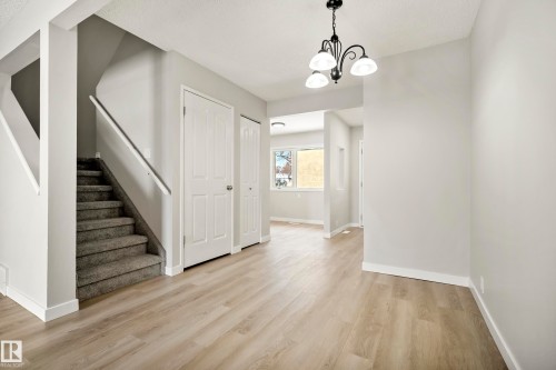 Spacious entryway featuring light-toned flooring, a carpeted staircase with a white handrail, and white paneled doors - 3311 139 Avenue, Edmonton, AB - Indoor Photo Showing Other Room