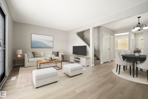 The living space features light wood-style flooring and a light-colored rug, with a staircase visible in the background - 3311 139 Avenue, Edmonton, AB - Indoor
