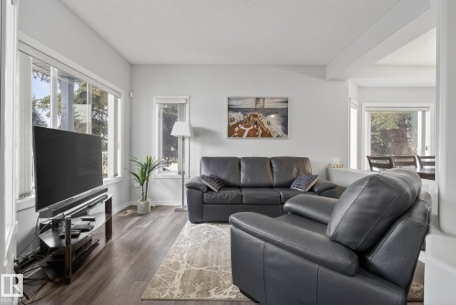 The living area features hard surface flooring, a decorative area rug, and ample natural light from several windows - 17204 113 Street, Edmonton, AB - Indoor Photo Showing Living Room