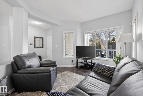 Living area featuring light gray walls, dark flooring, and a large window providing views of the outdoors - 17204 113 Street, Edmonton, AB - Indoor Photo Showing Living Room