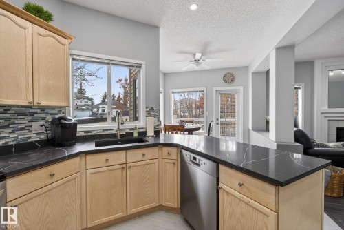 Kitchen featuring light wood cabinetry, dark countertops, and a mosaic tile backsplash - 17204 113 Street, Edmonton, AB - Indoor Photo Showing Kitchen