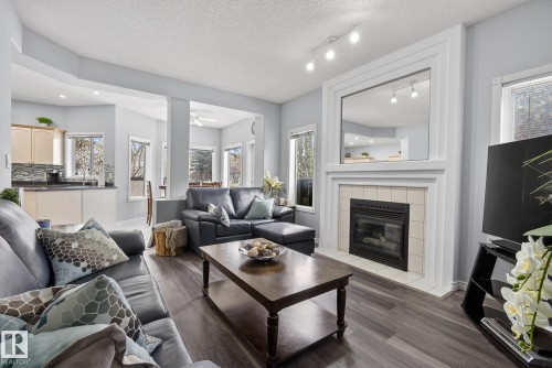 Living area featuring dark flooring, a fireplace with a tiled surround, and track lighting - 17204 113 Street, Edmonton, AB - Indoor Photo Showing Living Room With Fireplace