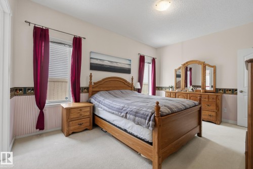 The room features a window with blinds and red curtains, and carpeted flooring - 17204 113 Street, Edmonton, AB - Indoor Photo Showing Bedroom