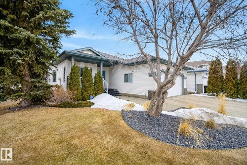 The property features a white exterior with a dark-colored roof and trim, a front porch with white railings, and a double garage - 17204 113 Street, Edmonton, AB - Outdoor