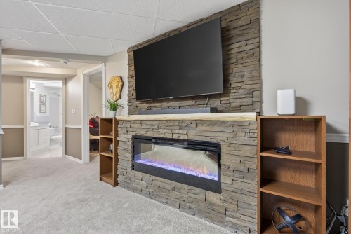 Living area featuring a stone accent wall with an integrated electric fireplace, flanked by wooden shelving - 17204 113 Street, Edmonton, AB - Indoor Photo Showing Living Room With Fireplace