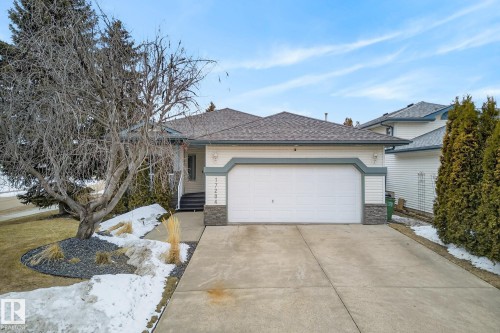 The property features a concrete driveway, an attached garage, and a light-colored exterior with stone accents - 17204 113 Street, Edmonton, AB - Outdoor